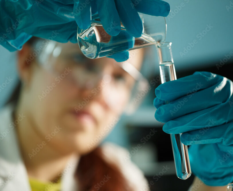A consumer product testing lab technician adds liquid to a test tube to conduct protein testing 